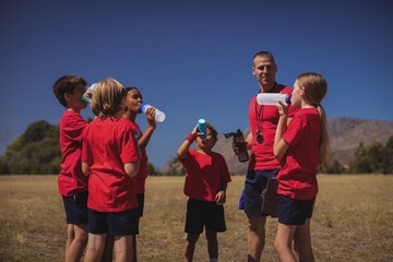 Wall Mural - trainer and kids drinking water in the boot camp