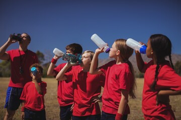 Wall Mural - trainer and kids drinking water in the boot camp