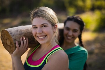 Wall Mural - Portrait of trainer and woman carrying heavy wooden log