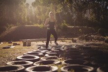 Woman running over tyres during obstacle course