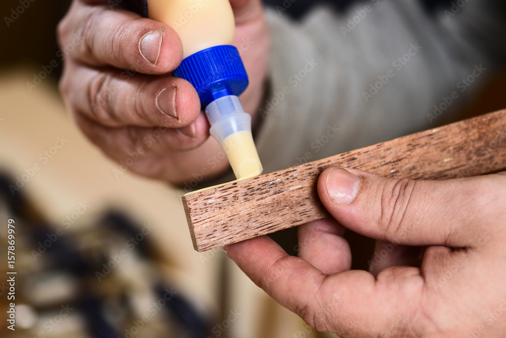 Carpenter applying glue on wooden detail - obrazy, fototapety, plakaty 