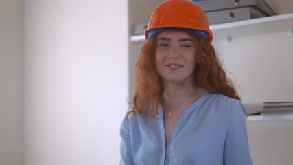Poster - Young redhead woman wearing helmet. Portrait attractive smiling engineer. Female looking at the camera and smiling.