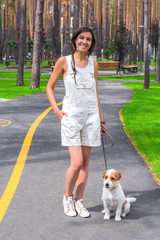 White dog and young woman posing in a park at summertime