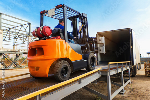 Obraz na plátně Forklift is putting cargo from warehouse to truck outdoors