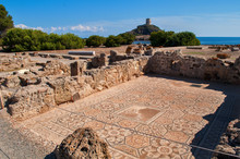 Excavations In Nora, Sardinia, Italy.  Mosaic Floor And Behind It An Old Watchtower On A Hill Above The Sea.