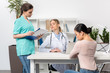 © LIGHTFIELD STUDIOS - Young patient sitting in chair and talking with doctor and nurse in medical office