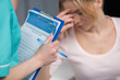 © LIGHTFIELD STUDIOS - Cropped shot of nurse holding clipboard and pen while upset patient sitting behind