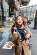 © EdNurg - Street portrait of smiling beautiful young woman buying fast food snacks at stall in europe