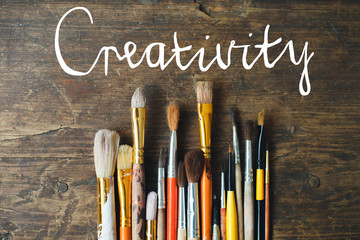 row of artist paintbrushes closeup on old wooden rustic table. Child creativity concept