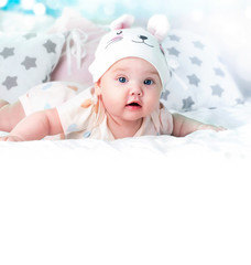 Wall Mural - Baby girl healthcare concept white background empty space.Infant portrait,child lying on bed.