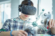 A caucasian student wearing a virtual reality headset interacts with a 3D scientific model.