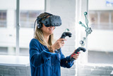 Fototapeta Sypialnia - A female student wearing a virtual reality headset interacts with a 3D scientific model.