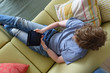 © rocklights - Teenager sitting on sofa playing on electronic device, Photo taken from above.