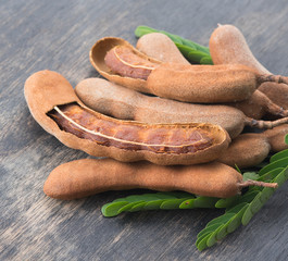 Sticker - Sweet ripe tamarind pods with tamarind leaves on wood background