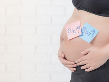 Pregnant Woman Waiting For A Boy Or Girl Against White Brick Wall