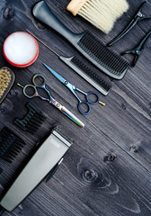 Hairdresser tools on wooden background. Top view on wooden table with scissors, comb, hairbrushes and hairclips, free space. Barbershop, manhood concept