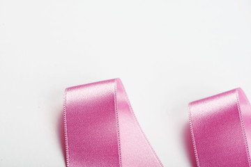 Pink ribbon with abstract shapes on white background. Isolated. Copy space.