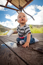 Baby Boy Spills A Styrofoam Cup Of Water Onto A Deck