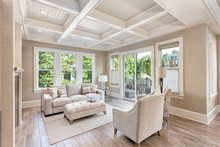 Beautiful Living Room With Hardwood Floors In New Luxury Home. Coffered Ceiling Adds Elegant Touch To This Furnished Living Space. Lush Trees Provide Scenic Exterior View. 