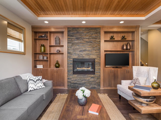 Beautiful living room with hardwood floors in new luxury home. Wood strip ceiling, fireplace, and wood built-ins make this the ideal venue for cozying up with a good book.