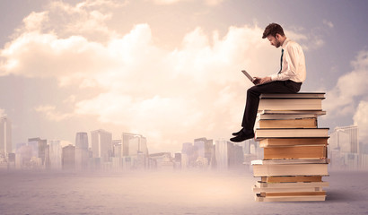 businessman with laptop sitting on books