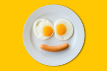 Smiling Face Frying Eggs Breakfast On A Plate Isolated Yellow Background.