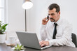 © bnenin - Middle aged man making call and using his laptop while working from home office