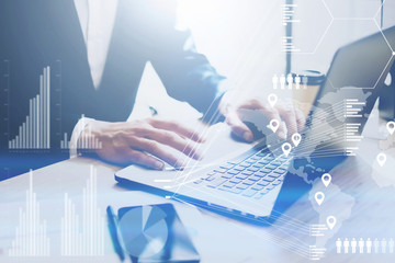 Concept of digital diagram,graph interfaces,virtual screen,connections icon.Businessman working at office on laptop at the wooden table.Male hand touching mobile computer touch pad.Blurred background.