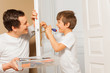 © Sergey Novikov - Man helping his son to draw up bolt of door handle