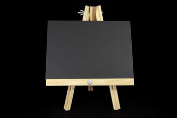 Wall Mural - Easel with blank black card on black background. Copy space.