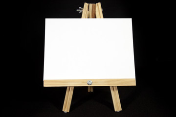 Wall Mural - Easel with blank white card on black background. Copy space.
