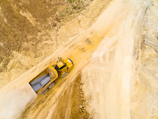 Wall Mural - Aerial view of truck on muddy road on a construction site. Heavy industry from above. Industrial background from devastated landscape.