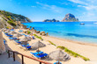 View of Cala d'Hort beach with sunbeds and umbrellas and beautiful azure blue sea water, Ibiza island, Spain