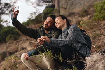 Wall Mural - Young couple out on hike in mountains taking selfie