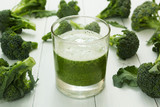Fototapeta Kuchnia - Glass of green smoothie and raw broccoli on white wooden background.