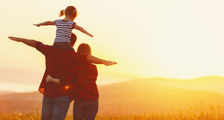 Happy family: mother father and child daughter on sunset