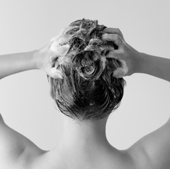 Wall Mural - Back of a woman in a shower shampooing her hair, massaging her head full of suds in black and white.