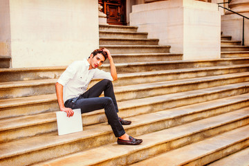 Wall Mural - Young Businessman sitting on stairs, relaxing outside