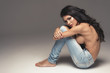 Sexy attractive brunette woman posing only in jeans in studio