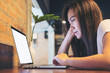 © Farknot Architect - Mockup image of a beautiful Asian woman using and looking at laptop with feeling stressed in modern loft cafe