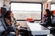 © EdNurg - Two woman Friends talks and laughing while travel by train
