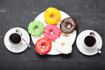 Wall Mural - Two cups with coffee and donuts on a black wooden table