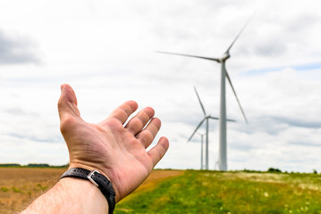 Human hand aiming to wind power turbines generate electricity