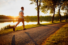 Young Man Jogging In Park During Sunset