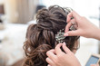 Hairdresser makes hairstyle bride