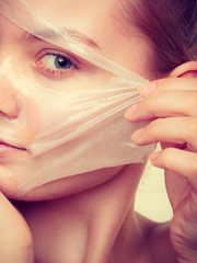 Woman removing facial peel off mask.