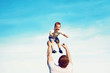 © guas - Happy father throws son child into the air, carefree having fun outdoors over the blue sky background, family, childhood, father's day - concept