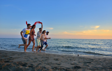 Wall Mural - Group of happy young people is running on background of sunset beach and sea