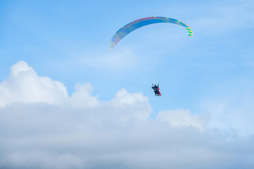 Paragliders in bright blue sky, tandem of instructor and beginner