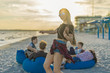 © Igor Kardasov - Party on the beach. Sexy girl with zizi cornrows dreadlocks dancing in the foreground, while man is playing on guitar to his friends. They sit on bean bags